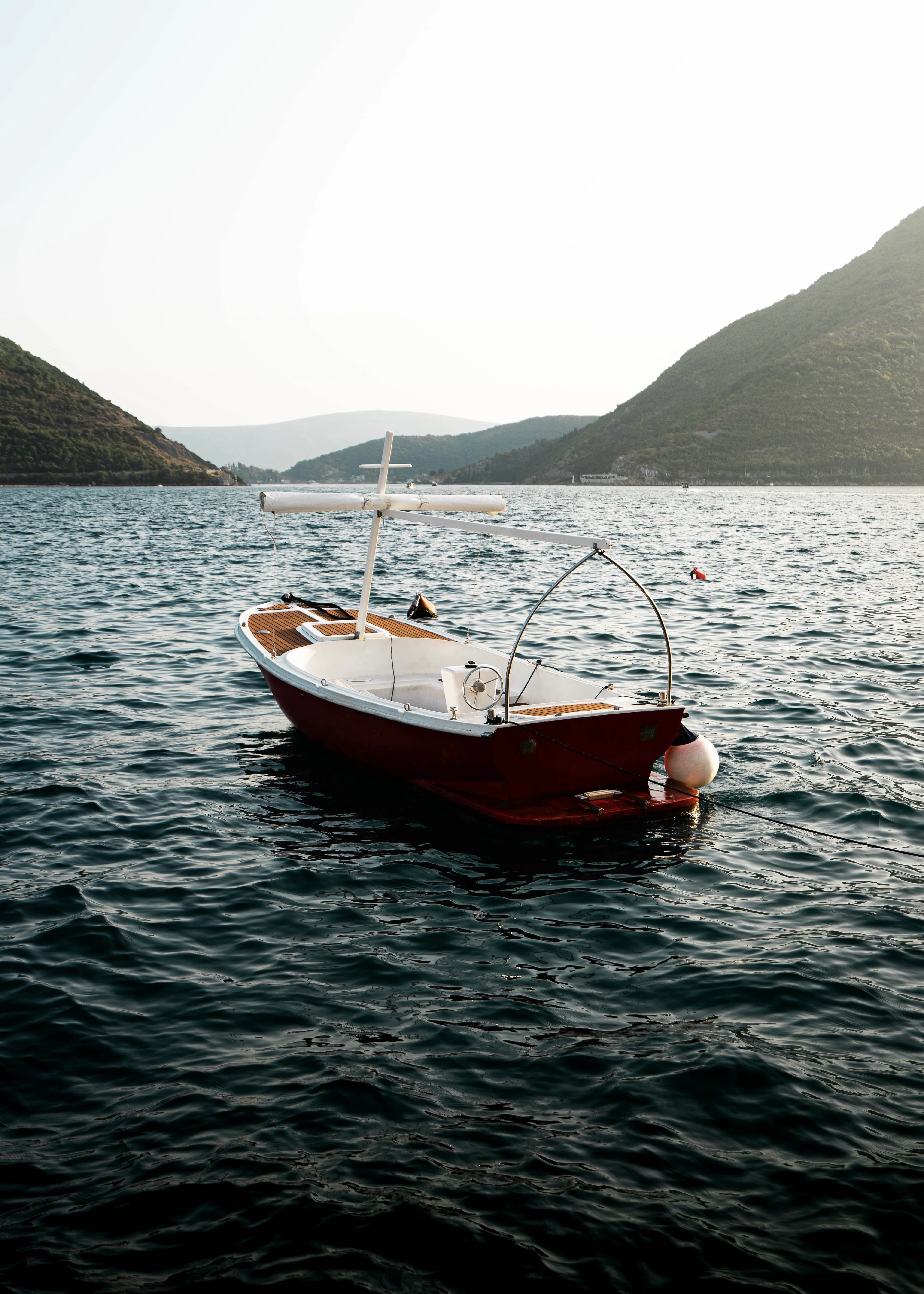 Small red boat moored on a calm dark-blue bay