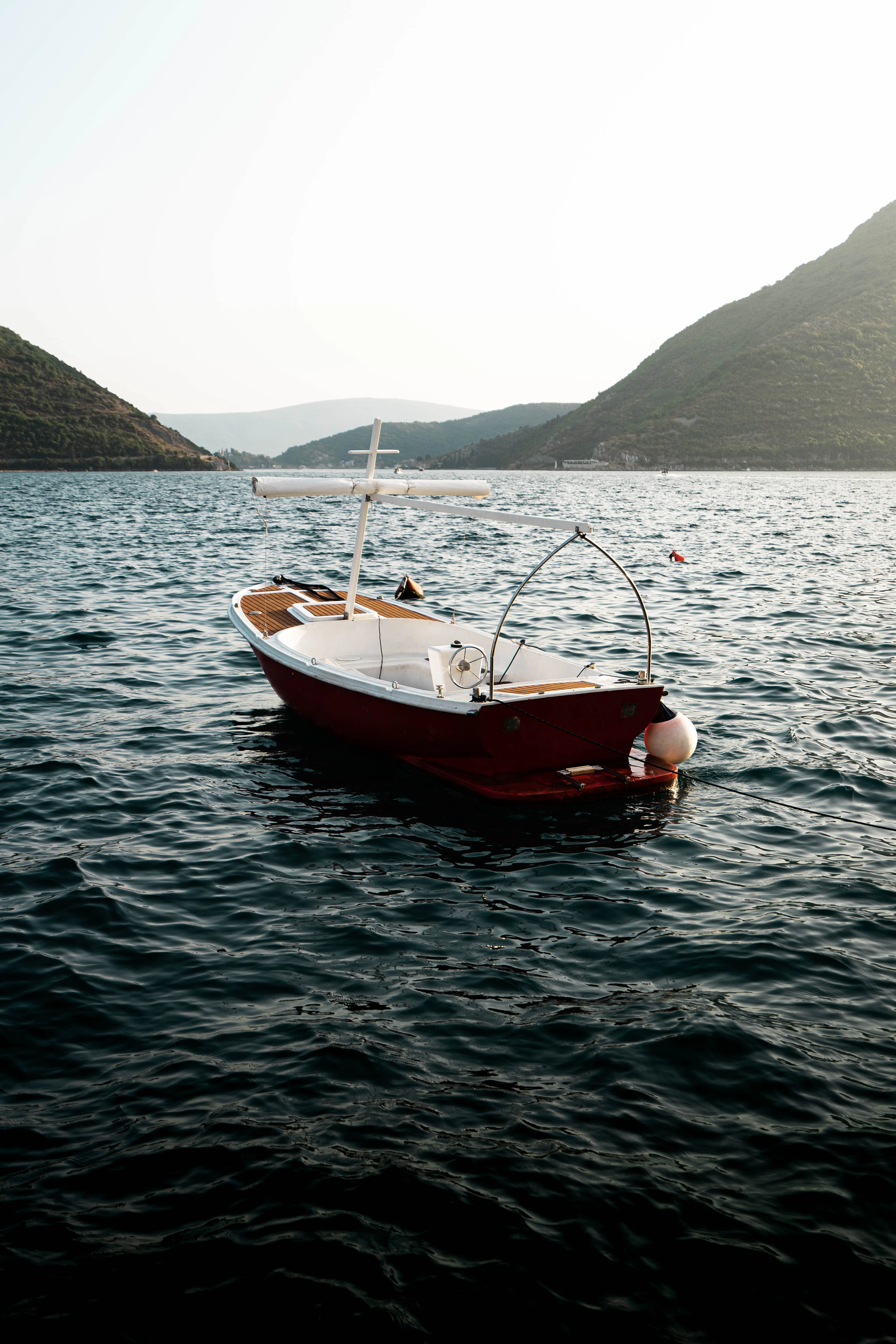 Small red boat moored on a calm dark-blue bay