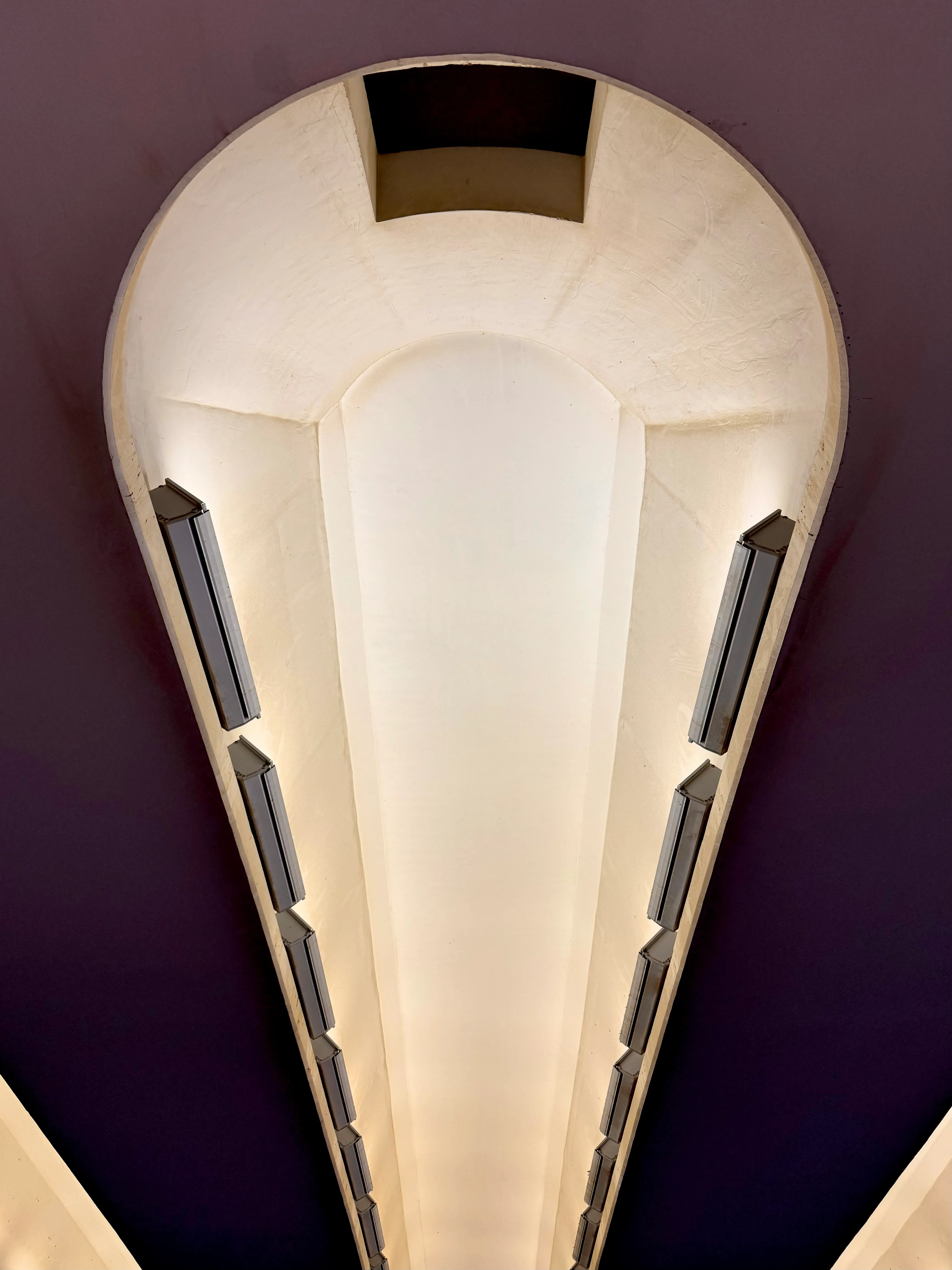 Cream art-deco ceiling light against a deep aubergine wall